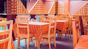 Un restaurante con mesas y sillas de madera, cubiertas con manteles a rayas.