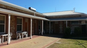 A two-story building with a brick facade, a covered patio area with plastic chairs, and a small lawn. - Sonbern Lodge Motel (Wallaroo)