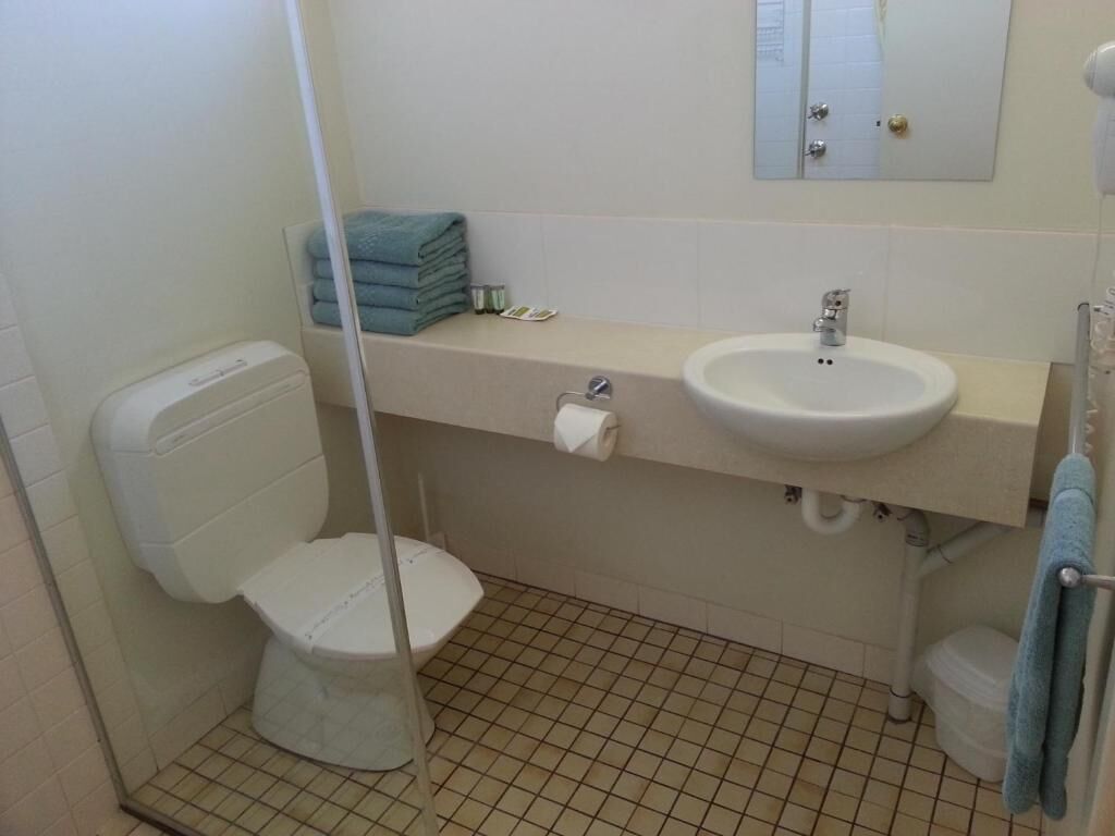 Un baño con inodoro, lavamanos y espejo.