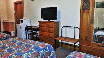 Un dormitorio con dos camas, un aparador de madera, un televisor y un microondas.