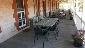 A covered outdoor seating area with tables and chairs, air conditioning units, and potted plants. - Sonbern Lodge Motel (Wallaroo)