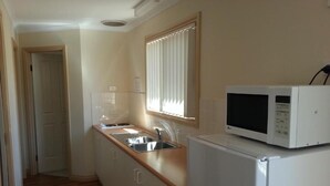 A compact kitchen with a microwave, sink, and refrigerator. - Sonbern Lodge Motel (Wallaroo)