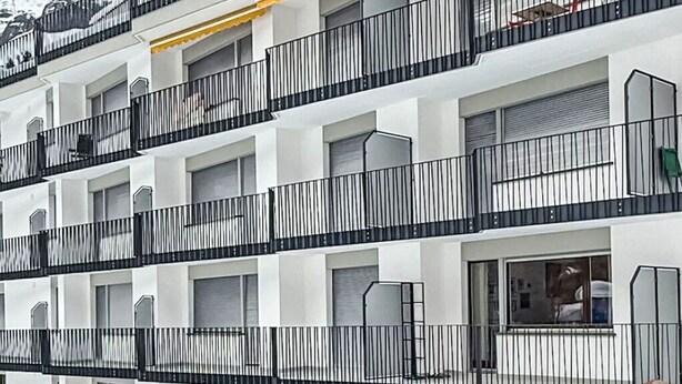 A multi-story hotel with balconies, a wooden fence, and snow-covered ground.