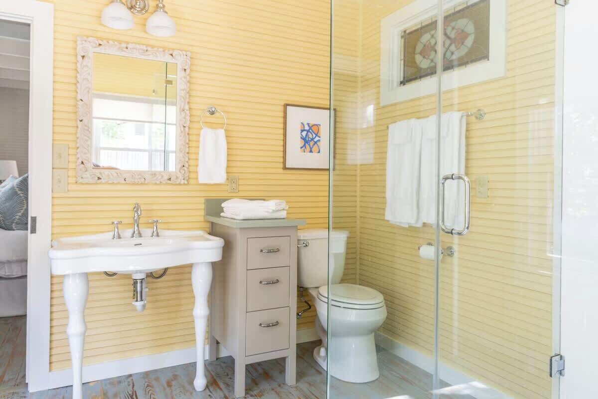 Une salle de bain équipée d’un lavabo, d’un meuble-vasque, de toilettes et d’une douche à parois en verre.