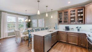 Una cocina moderna con una isla central, armarios de madera e iluminación colgante.
