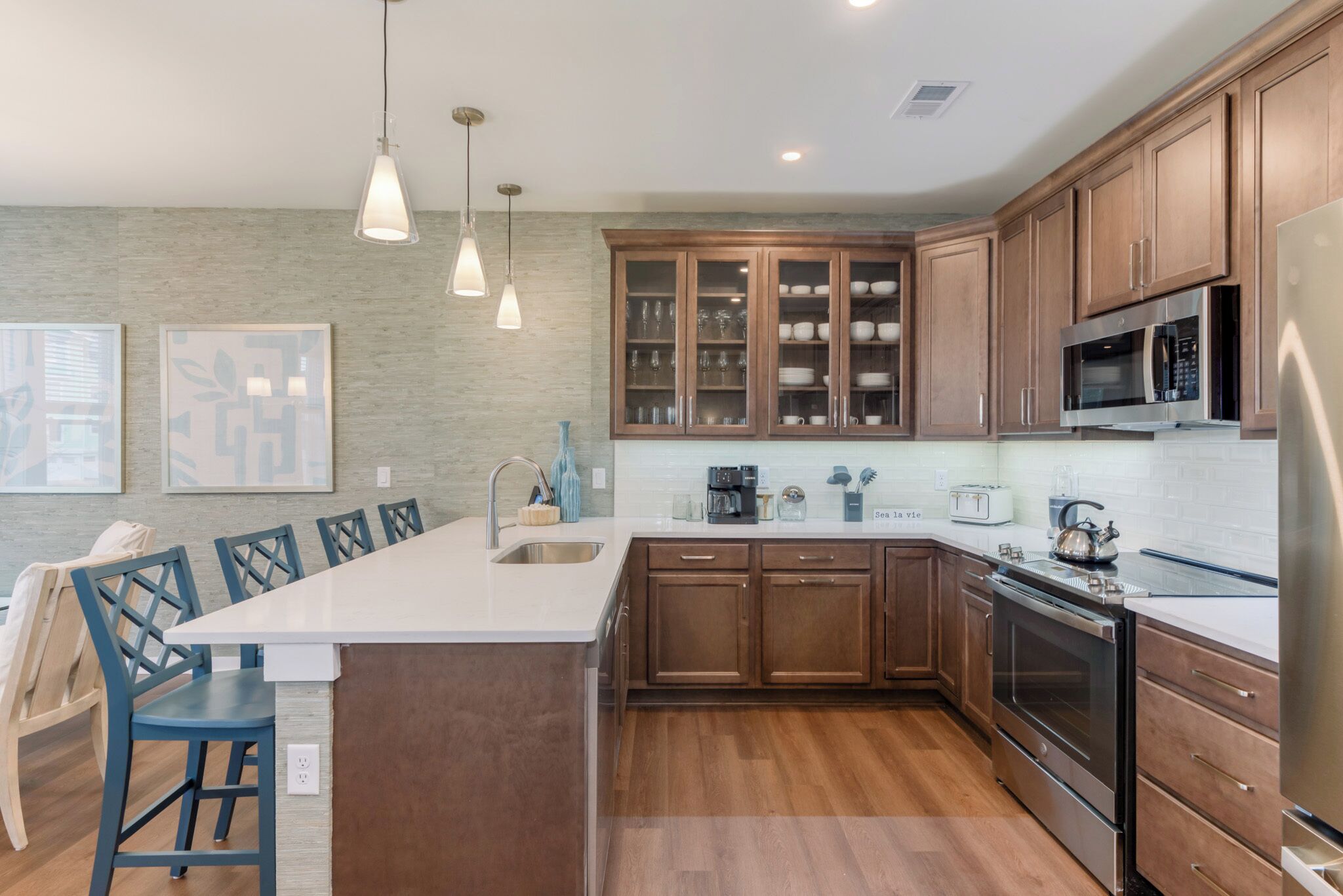 A modern kitchen with wooden cabinets, stainless steel appliances, and a central island with seating.