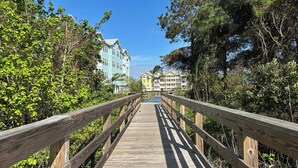 Un paseo marítimo de madera que conduce a una hilera de edificios con varios pisos y balcones.