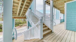 A wooden deck with a white staircase leading to a covered area.