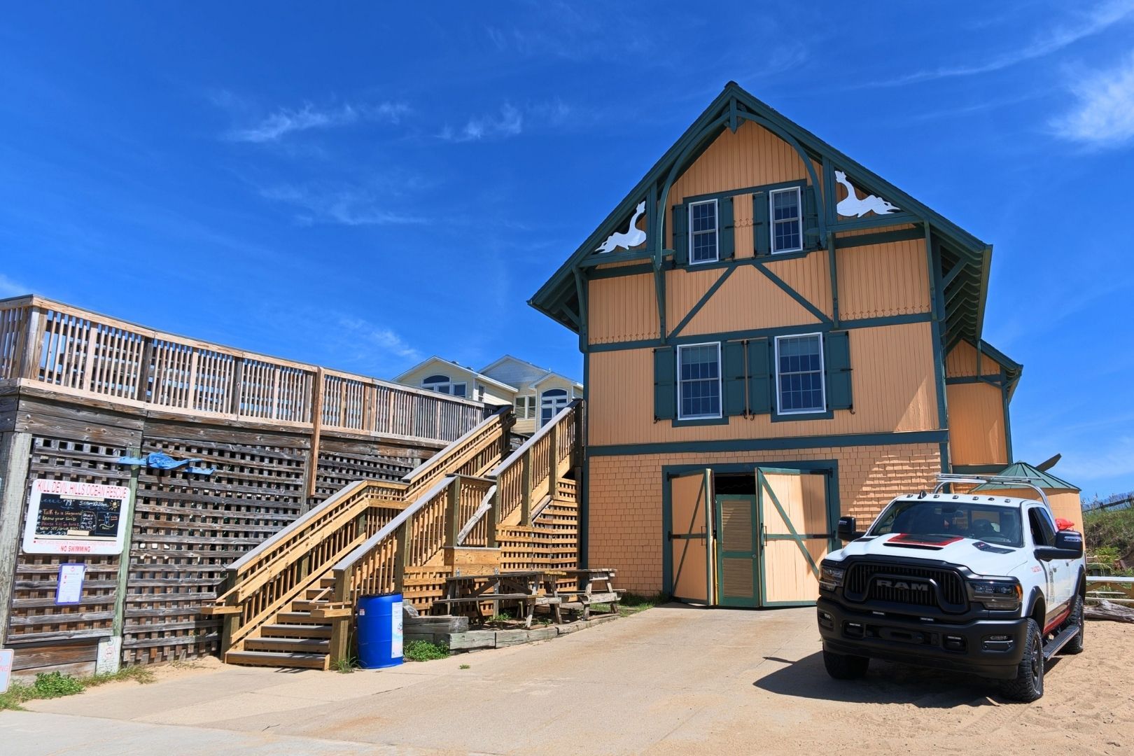 A building with a wooden exterior, a ramp leading to a deck, and a parked truck.