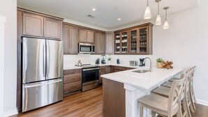 A modern kitchen with stainless steel appliances, wooden cabinets, and a central island with seating.