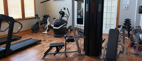A gym with various exercise equipment, including treadmills, a stationary bike, and weight machines.