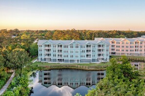 Un hôtel à plusieurs étages offrant une vue sur le front de mer, doté de balcons et d’un bassin décoratif.