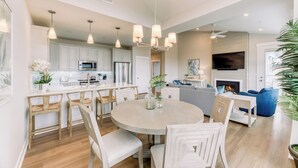 Une cuisine moderne avec des meubles blancs, des appareils en acier inoxydable et un îlot central doté de tabourets de bar.