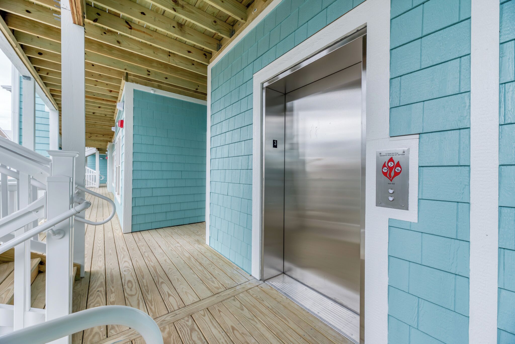 An elevator in a building with teal walls and wooden flooring.