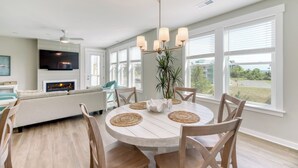 A modern dining area with a round table, chairs, and a ceiling fan.