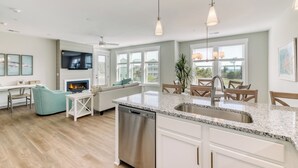 A modern kitchen with a central island, built-in dishwasher, and a dining area with wooden chairs and a table.