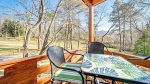 A wooden deck with two chairs and a table, overlooking a forested area. - Charming 2-bedroom cottage with AC, WiFi in welcoming Waynesville (Waynesville)