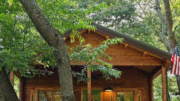 A wooden cabin with a porch, surrounded by trees. - Charming 2-bedroom cottage with AC, WiFi in welcoming Waynesville (Waynesville)