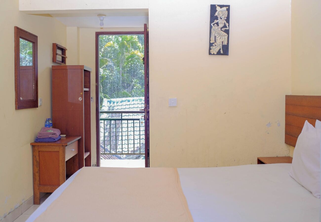 Une chambre à coucher comprenant un lit, une table de chevet, une armoire et une porte donnant sur un balcon.