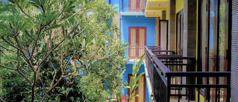 A multi-story building with balconies and a tree in the foreground.