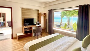 A hotel room with a bed, a desk, a TV, and a window with a view of the sea. - Comfy Cool Breeze by eMzaz (Dhiffushi)