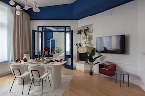 A modern living room with a dining area, a fireplace, and a TV mounted on the wall. - Head in the Clouds by Fragola Apartments (Kraków)