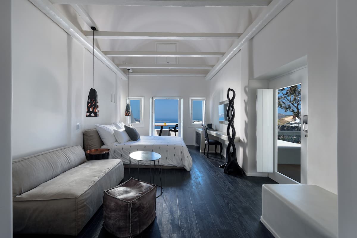 A modern, well-lit room with a bed, sofa, and a desk area.