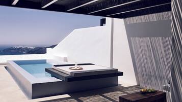 Un espace de détente extérieur moderne, doté d’une piscine, d’un coin salon avec une table basse et d’une petite table sur laquelle sont disposés des fruits.