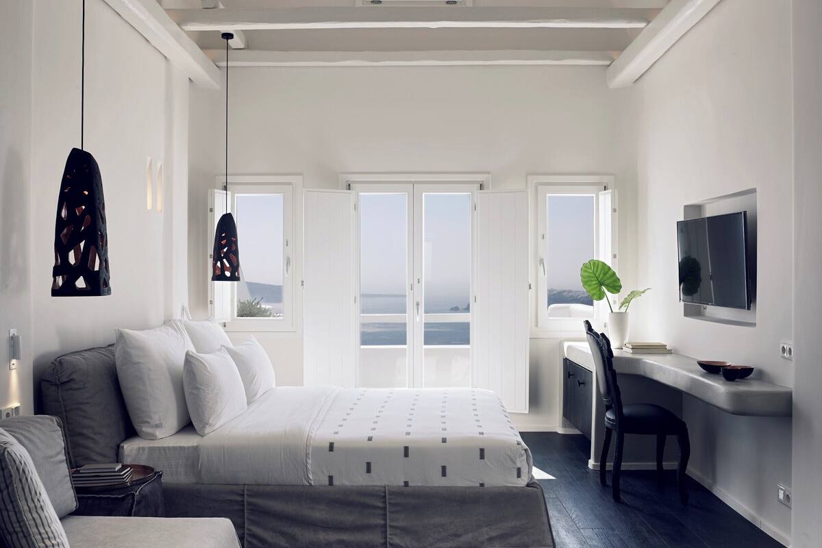 A modern bedroom with a large bed, a desk, and a TV.