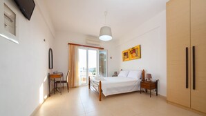 A bedroom with a bed, bedside table, lamp, wardrobe, and a window with curtains.