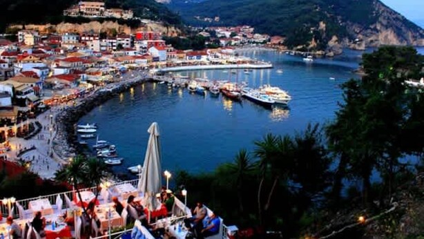 Une ville côtière dotée d’un port de plaisance, de bateaux et d’un espace de restauration avec des tables et des parasols.