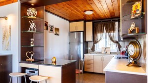 A compact kitchen with wooden ceiling, a central island with stools, and a refrigerator. - Seaview Nature Retreat - Filiatra s Cozy Hideaway (Trifylia)