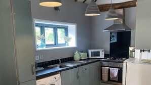 A modern kitchen with a built-in washer, a microwave, and a stove. There are pendant lights, a window with flowers, and a view of the outdoors.