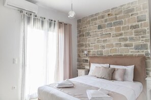 Una camera da letto con parete in pietra, un letto con lenzuola bianche, un comodino e un lampadario.
