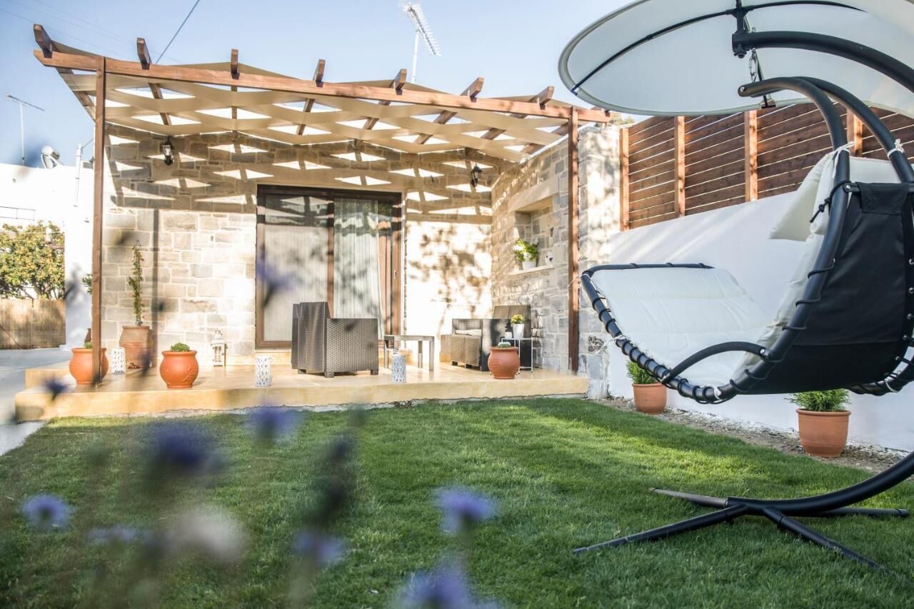 A patio area with a pergola, outdoor seating, and a hanging chair.