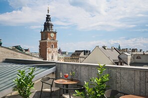 Una terraza en la azotea con mesa, sillas y una planta en maceta.