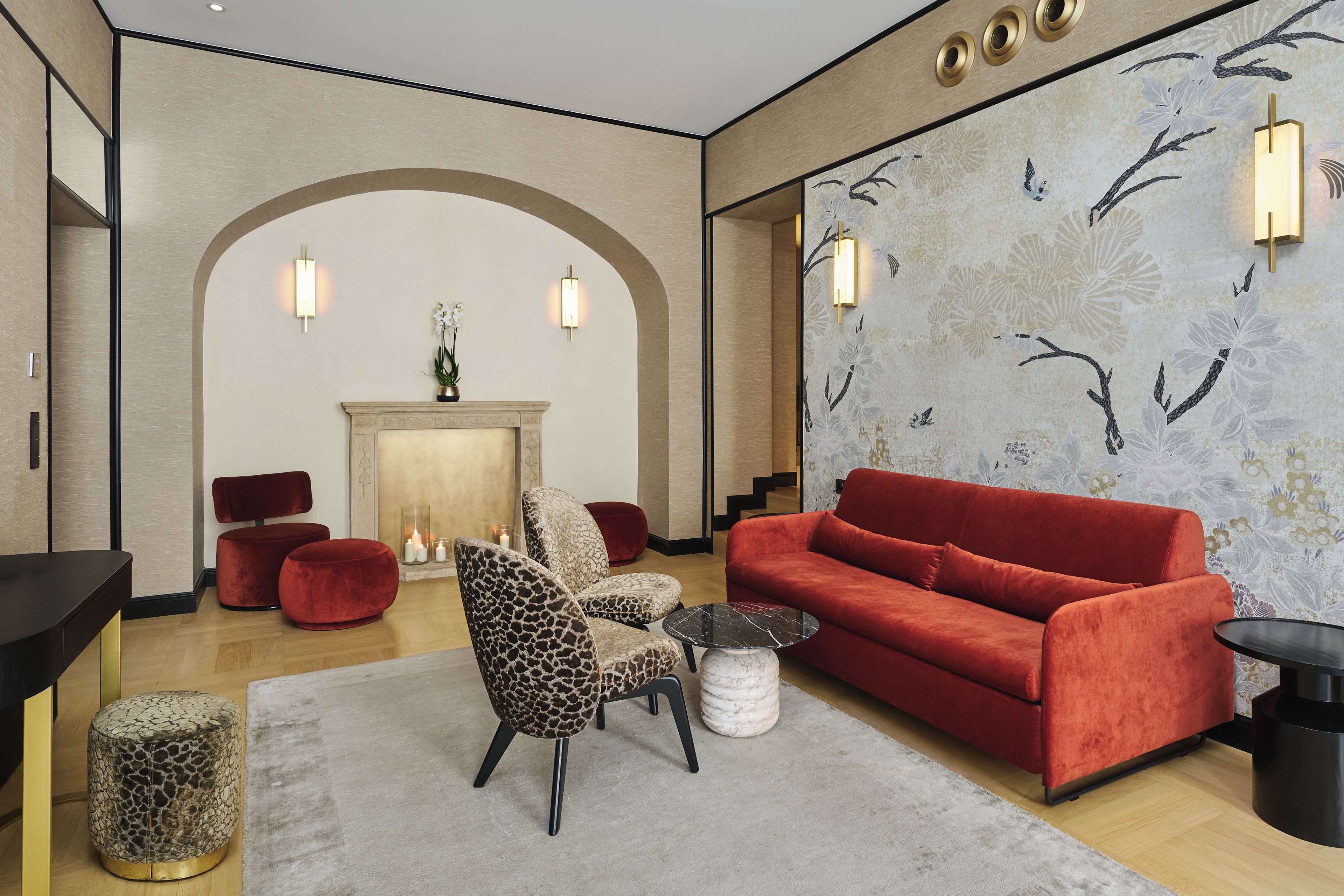 Una sala de estar moderna con un sofá rojo, un sillón estampado de leopardo y una chimenea.