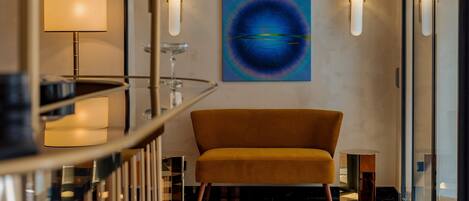 A lobby with a checkered floor, a mustard-colored sofa, and a large abstract painting on the wall.