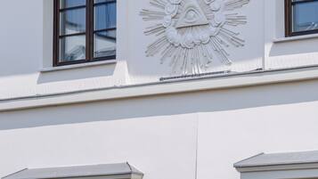 A building facade with a decorative sunburst motif and three windows with wooden frames.