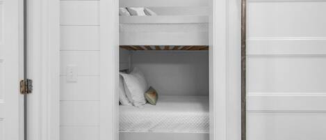 A white room with a bunk bed and a door.