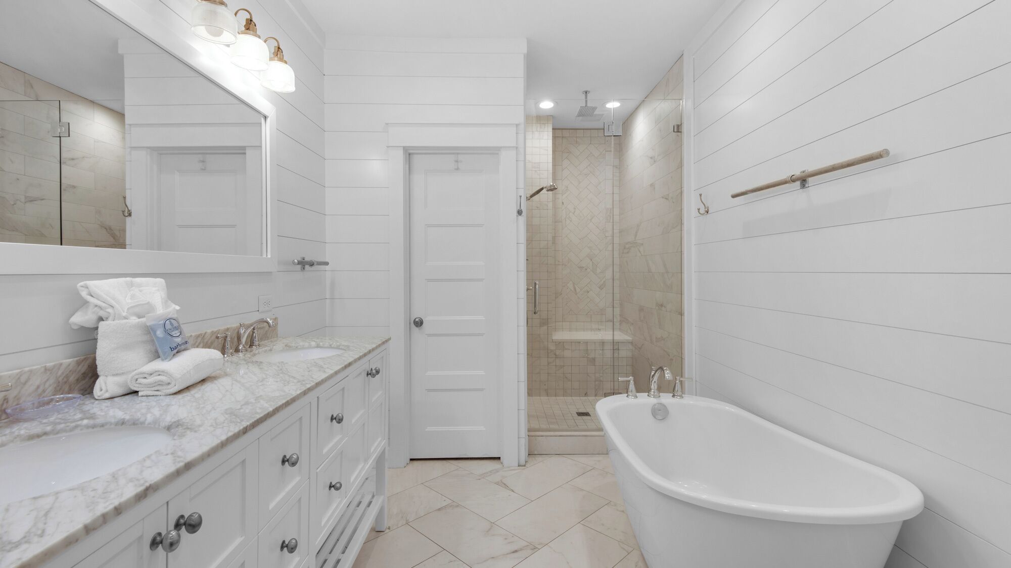 Un baño moderno con tocador de mármol, bañera independiente y ducha a ras de suelo.