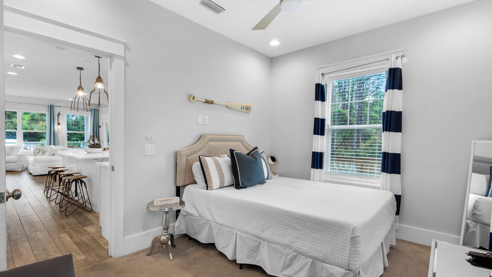 A modern bedroom with a large bed, a small table, and a window with curtains.