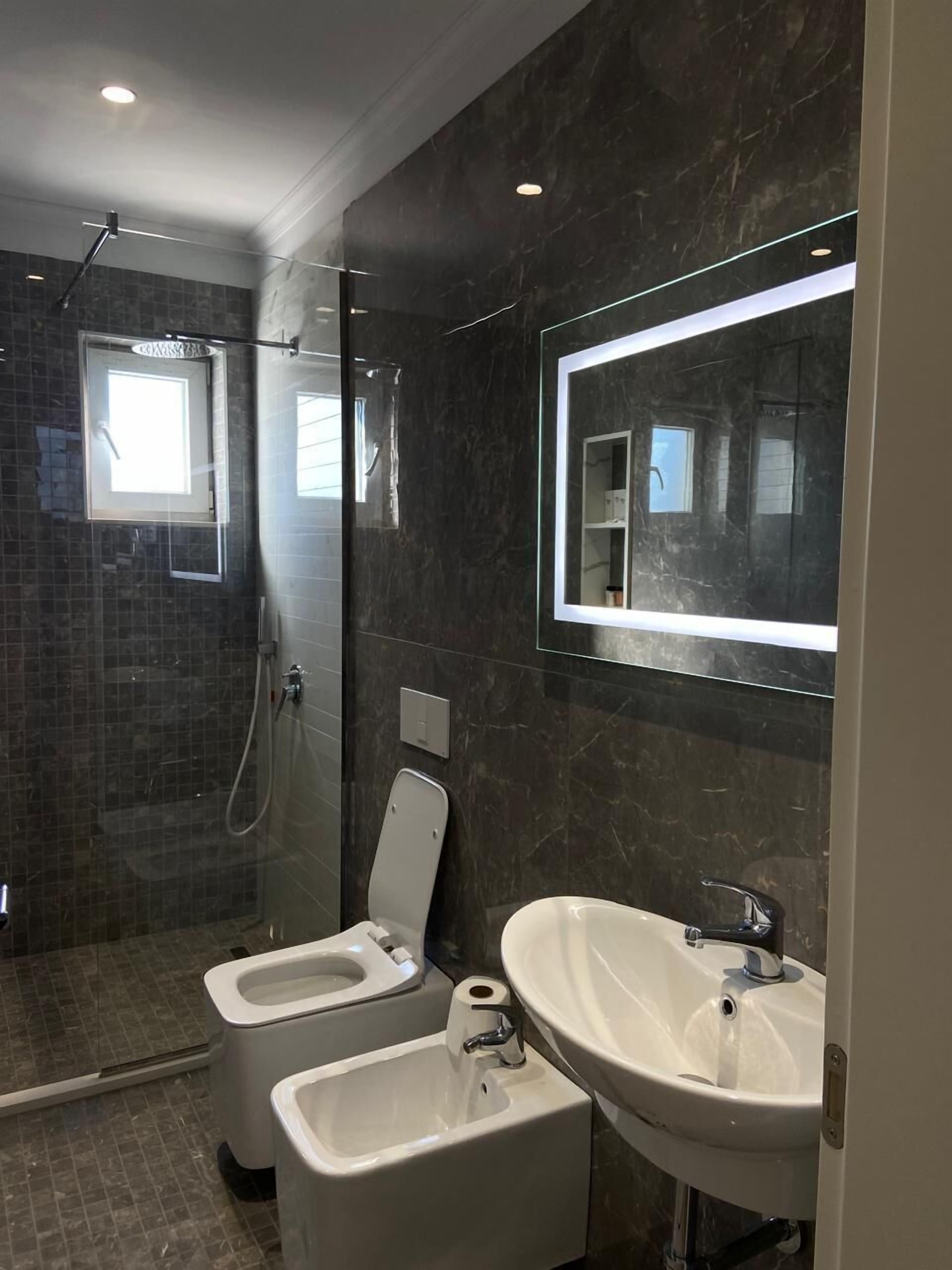 A modern bathroom with a glass-enclosed shower, two sinks, and a large mirror.