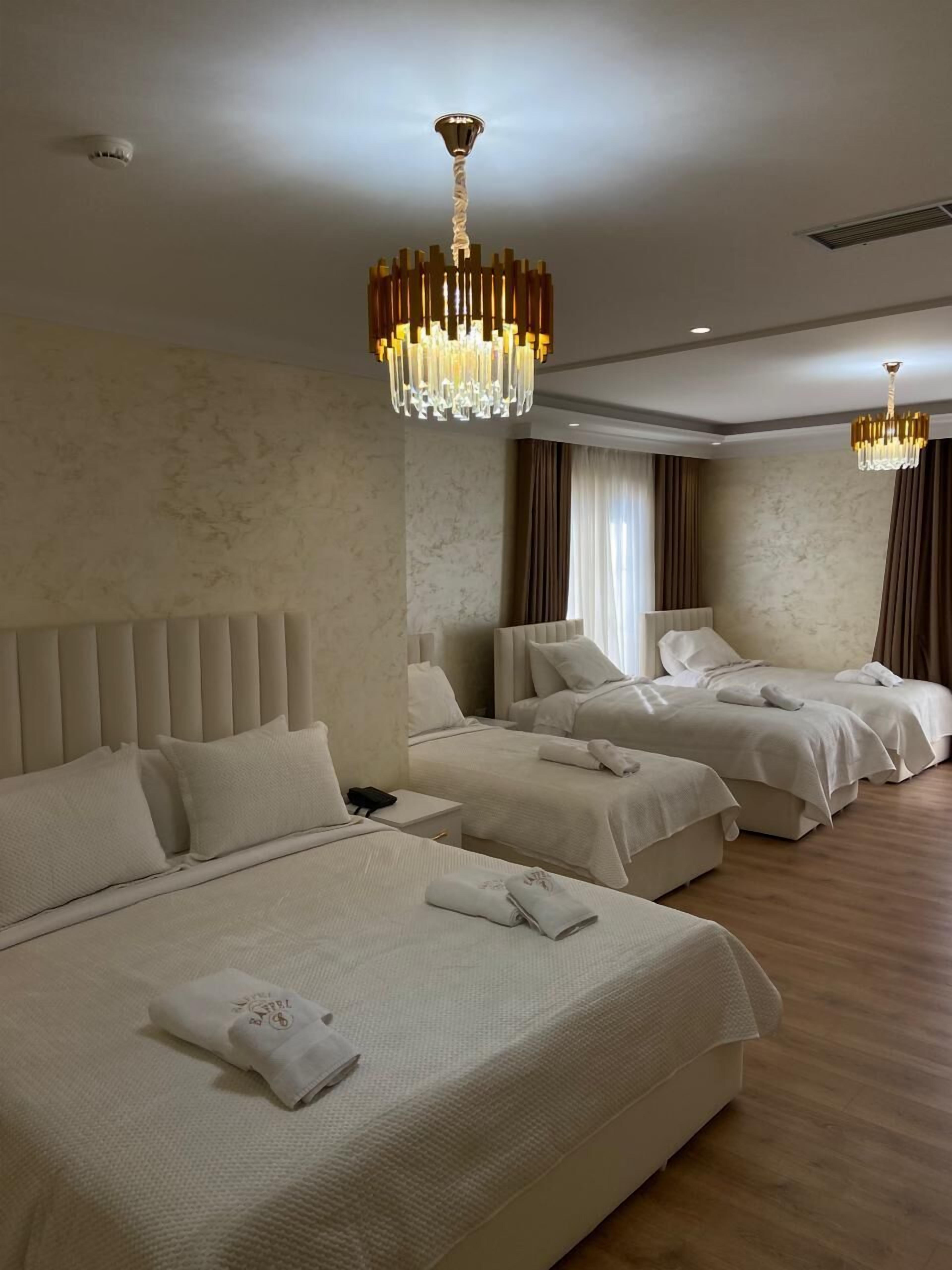 A hotel room with three beds, a large chandelier, and a marble wall.