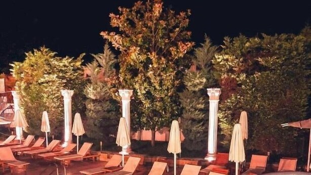 A swimming pool with lounge chairs and umbrellas, surrounded by trees and columns. - Hotel Eiffel (Kashar)