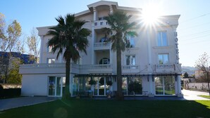 A multi-story hotel with balconies, large windows, and palm trees in the front yard. - Hotel Eiffel (Kashar)