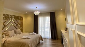 A hotel room with a bed, a chandelier, a wooden floor, and a view of the outdoors through the window. - Hotel Eiffel (Kashar)