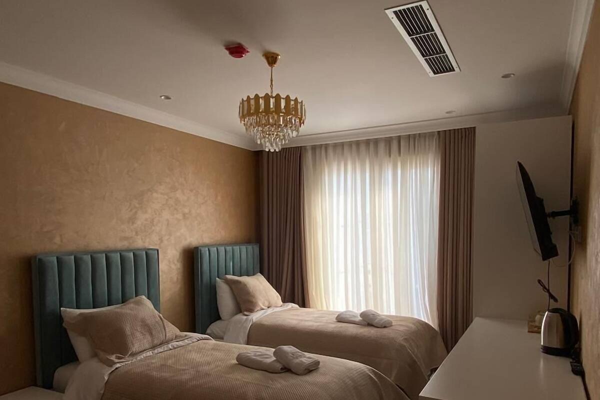 Ein Hotelzimmer mit zwei Betten, einem Schreibtisch, einem Fernseher und einer Kandelaber.