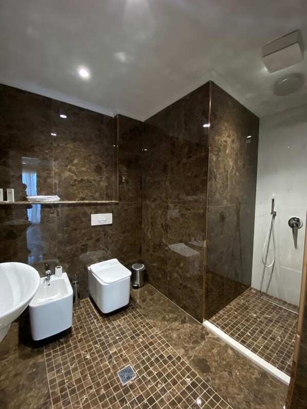 A modern bathroom with a large mirror, a bathtub, a shower, and a toilet. - Hotel Eiffel (Kashar)