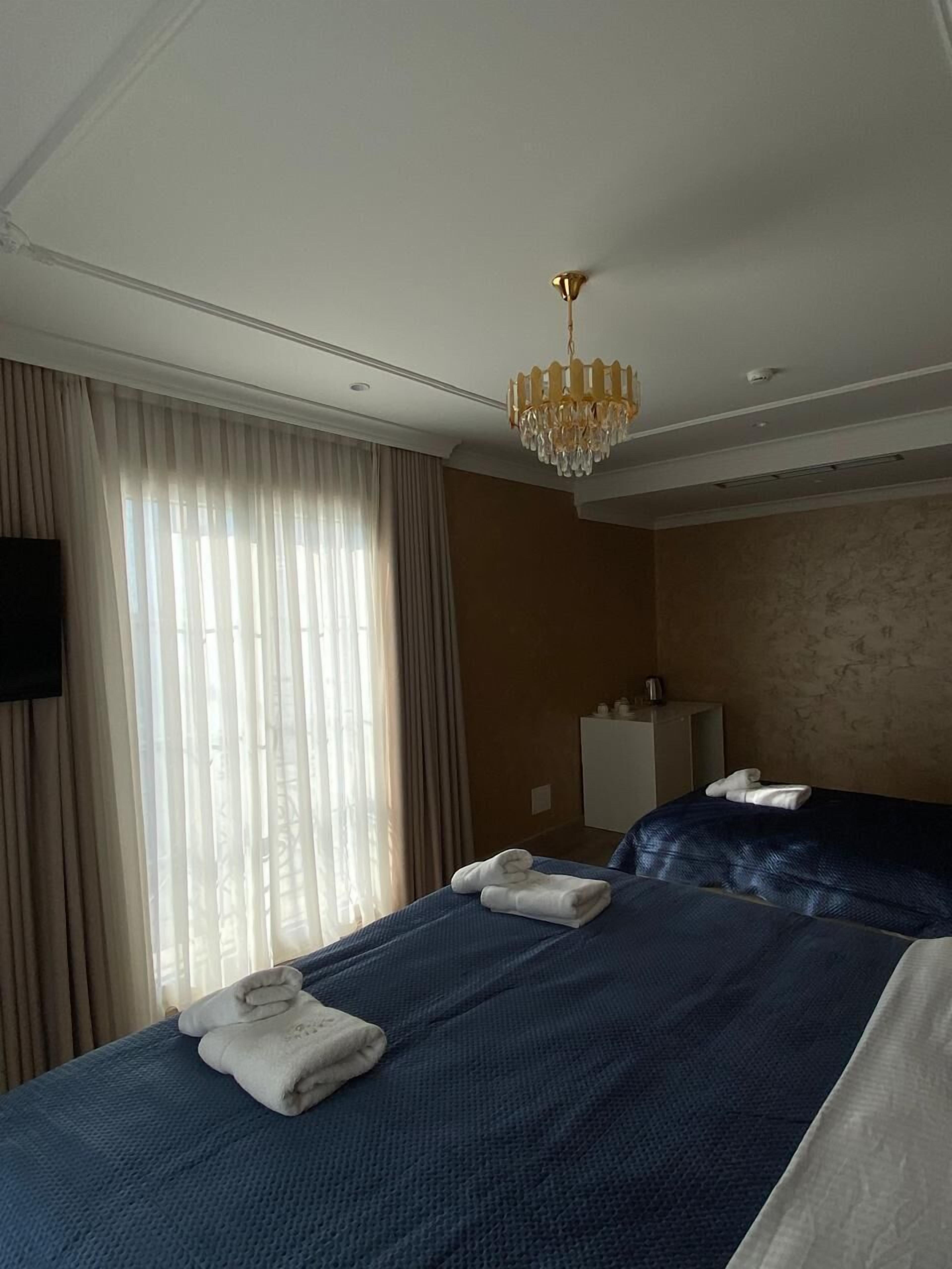 A hotel room with two beds, a chandelier, a television, and a minibar.